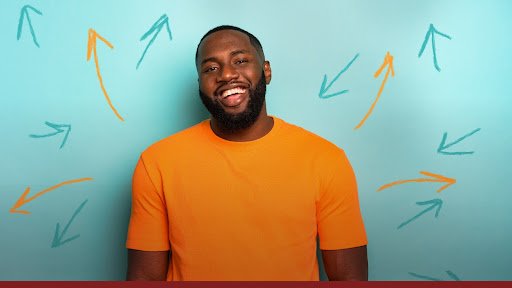 black man wearing a bright orange t-shirt smiling to the camera